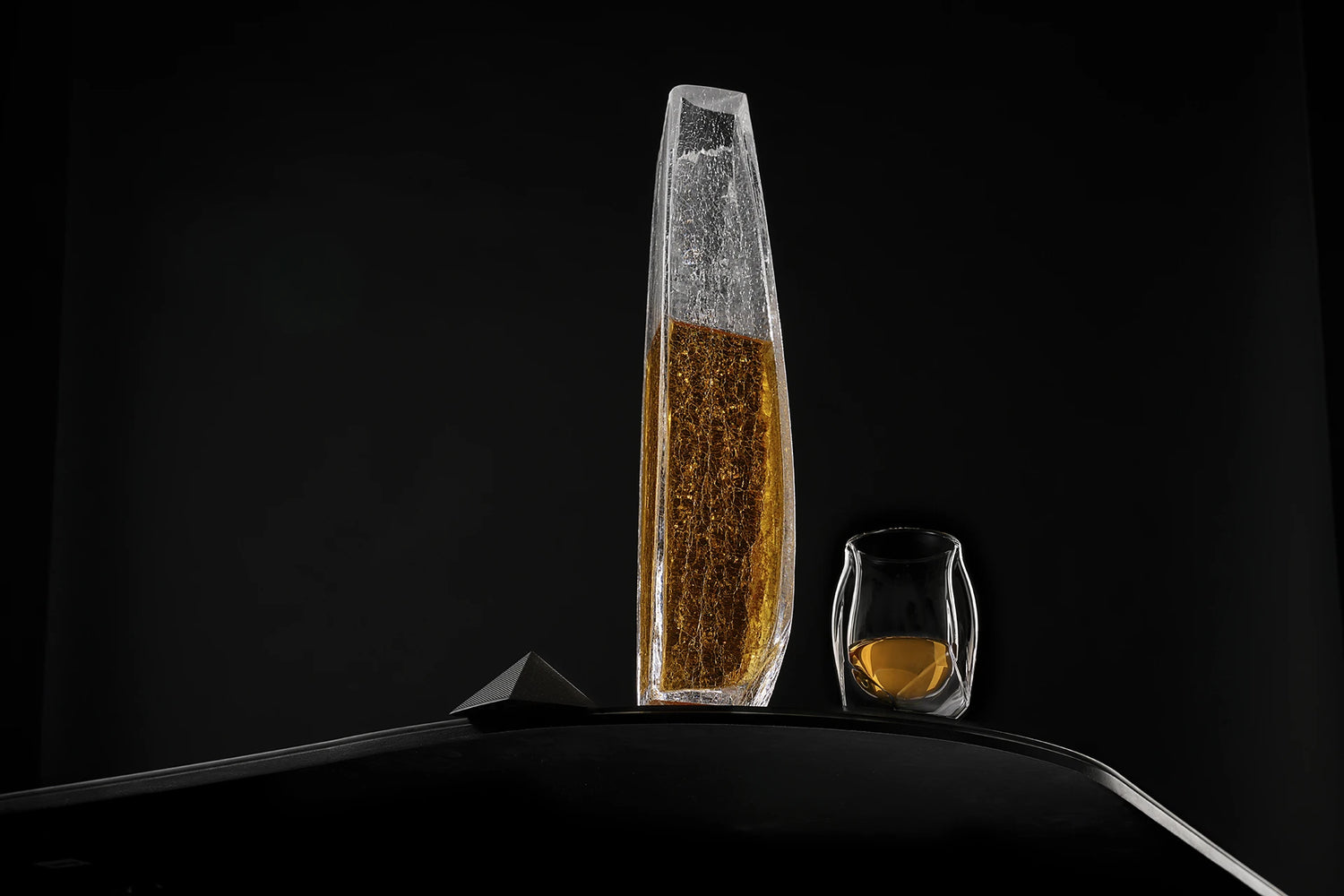 A panoramic shot of the Raif Whisky Decanter - Crackle Edition with whisky shot next to the Norlan Whisky Glass (Clear). A perfect pairing.