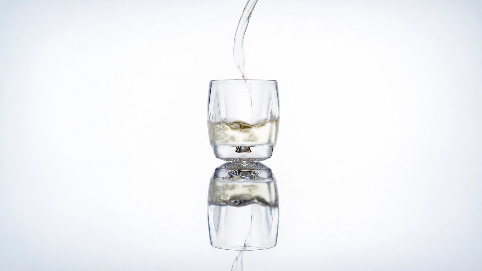 Norlan Rauk Heavy Tumbler 250 mL (Clear) with whisky being poured, reflected on a light background.