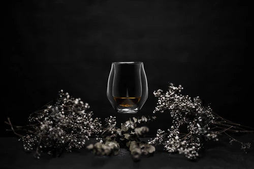 Lifestyle image of the Norlan Whisky Glass in Clear floating in the center of a white floral arrangement.