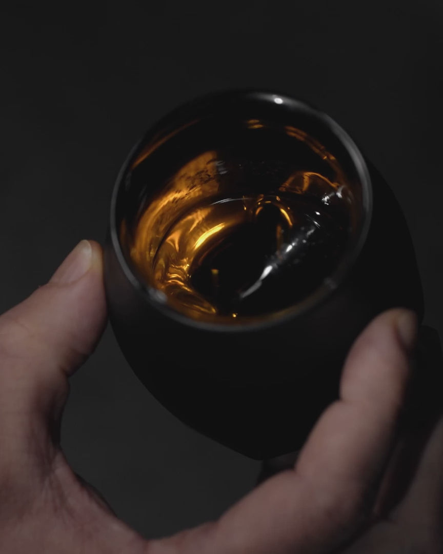 A whiskey enthusiast holding the VAILD edition of the Norlan Whisky Glass, swirling the amber gold, a unique feature of the glass is revealed. When exposed to a singular sight source, the contents of the glass appear to be illuminated.